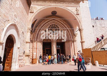 Seiteneingang der unteren Basilika San Francesco d'Assisi, Umbrien, Italien, mit Menschen. Touristen vor dem Eingang zur Kirche von San Francisco Stockfoto