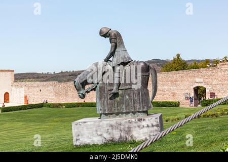 Bronzestatue eines Ritters auf dem Pferderücken vor der Basilika des Heiligen Franziskus von Assisi. Statue des besiegten Ritters. Stockfoto