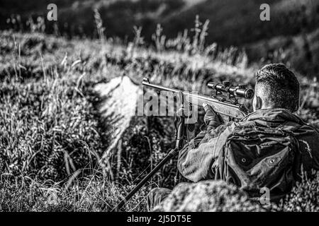 Jagdzeit. Männlich mit einer Waffe. Nahaufnahme. Jäger mit Jagdgewehr und Jagdform zur Jagd. Hunter zielt. Shooter Sichtung in das Ziel. Der Mann Stockfoto