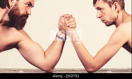 Zwei Männerhände umklammten Arm Wrestling, stark und schwach, ungleiche Übereinstimmung. Stark muskulös bärtigen Mann Arm Ringen ein mickrigen schwachen Mann. Arme ringen dünn Stockfoto