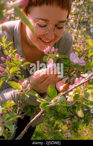 Schöne junge Frau, die die Schönheit der blühenden Apfelbäume im Frühling in Südtirol, Italien, genießt Stockfoto