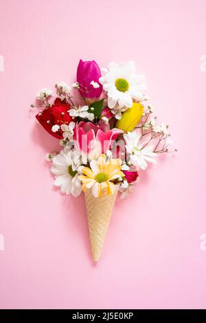 Frühlingsblumen in Eiskegel auf rosa Hintergrund Stockfoto