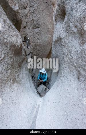 Ein junger Wanderer steht am Fuße der Kletterringe in einem Slot Canyon auf dem Rings Loop Trail im Mojave National Preserve, einer spaßigen Familienwanderung in Kalifornien Stockfoto