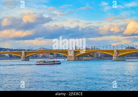 Die Barge schwebt unter der historischen gelben Margaretenbrücke über die Donau, Budapest, Ungarn Stockfoto
