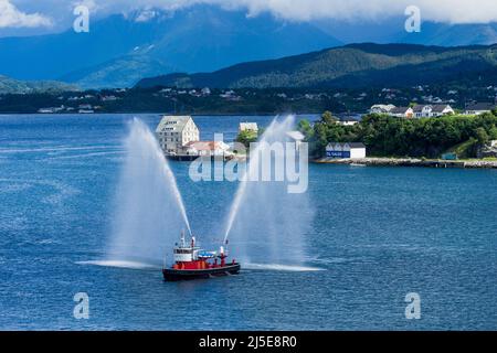 Vintage Fire Boat in Alesund, Norwegen, das einem Schiff durch Sprühen seiner Jets einen Abgang gibt. Stockfoto