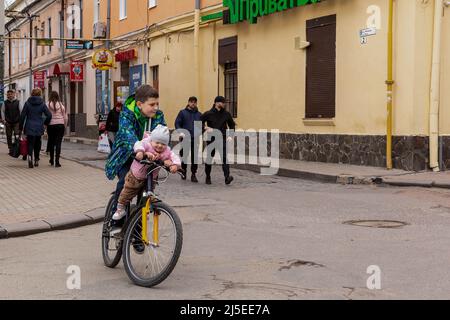 Sambir, Gebiet Lwiw, Ukraine. 22. April 2022. Ein ukrainischer Junge mit einem Baby sah an einem orthodoxen Karfreitag Fahrrad auf einem Hauptmarkt fahren. Als die Russische Föderation vor fast zwei Monaten in die Ukraine einmarschierte, hatte der Konflikt Auswirkungen auf alle Gebiete des Landes. Dennoch gilt die westliche Ukraine mit ihrer Region Lwiw als sicherer Himmel im Vergleich zum östlichen Teil des Landes. (Bild: © Dominika Zarzycka/SOPA Bilder via ZUMA Press Wire) Bild: ZUMA Press, Inc./Alamy Live News Stockfoto