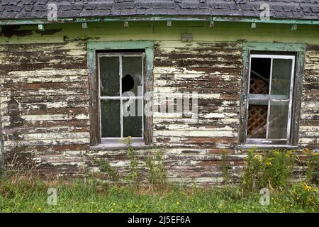 Alte Scheune mit zwei kaputten Fenstern und Peeling Paint Stockfoto
