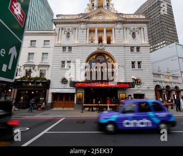 London, Greater London, England, 13 2022. April: Victoria Palace Theatre, Außenansicht Abendzeit, wenn ein Taxi mit Bewegungsunschärfen vorbei fährt. Victoria Street. Stockfoto