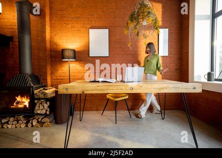 Frau sitzt am Tisch im Wohnzimmer im Loft-Stil Stockfoto