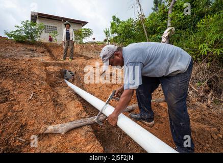 Bauarbeiter legen in Las Minas de Tulu, Provinz Cocle, Republik Panama, Mittelamerika, eine an eine Klärgrube angeschlossene Klärröhre. Stockfoto