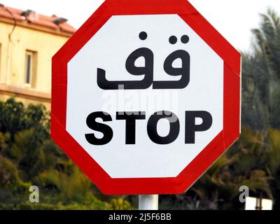 Zweisprachiges arabisches und englisches STOPPSCHILD Tafel mit arabischer Textskript und englischer Übersetzung (Stop) mit einer Achteck-Form, einem Straßenverkehrssymbol für ein Stockfoto