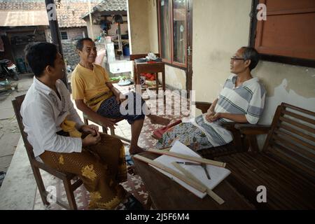 I Wayan Edi Wistara (rechts) und seine Verwandten erhalten Erhaltung inmitten seiner Tätigkeit, alte balinesische Texte in Palmblätter in Karangasem, Bali, Indonesien, umzuschreiben. Stockfoto