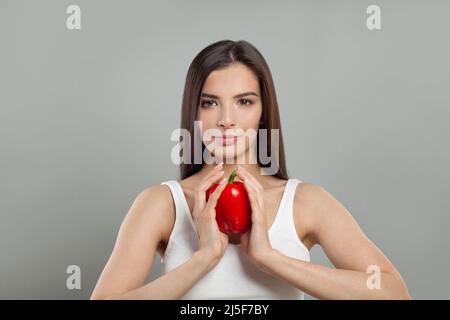 Nette Frau hält rote Paprika auf grauen Studio Wand Hintergrund Stockfoto