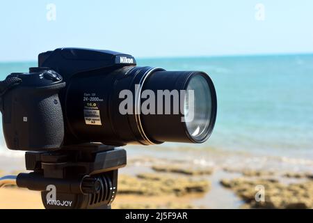 Sinai, Ägypten, August 23 2018: Eine Nikon-Digitalkamera auf einem Stativ filmt und zeichnet eine natürliche Szene auf einem Strand des Süd-Sinai vor den roten s auf Stockfoto