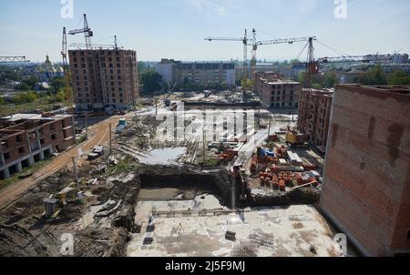Panoramablick auf das Stadtgebiet mit neu gebauten Wohngebäuden und Turmdrehkranen. Stadtstraßen mit Baustelle, Wohngebäuden, Baumaterialien und Kränen. Stockfoto