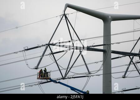 Bridgwater, Somerset, Großbritannien. 23.. April 2022. Arbeiter auf einer Luftplattform, die an einem der neuen National Grid T-Masten in Bridgwater in Somerset arbeitet, die als Teil des Hinkley Point C über die Somerset-Ebenen gebaut wurden.Bildquelle: Graham Hunt/Alamy Live News Stockfoto