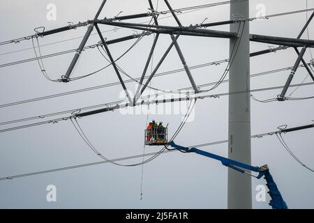 Bridgwater, Somerset, Großbritannien. 23.. April 2022. Arbeiter auf einer Luftplattform, die an einem der neuen National Grid T-Masten in Bridgwater in Somerset arbeitet, die als Teil des Hinkley Point C über die Somerset-Ebenen gebaut wurden.Bildquelle: Graham Hunt/Alamy Live News Stockfoto