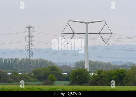 Bridgwater, Somerset, Großbritannien. 23.. April 2022. Gesamtansicht eines der neuen National Grid T-Masten bei Bridgwater in Somerset, die im Rahmen des Projekts des Kernkraftwerks Hinkley Point C über die Somerset-Ebenen gebaut wurden. In der Nähe befindet sich einer der traditionellen Gittermasten. Bildnachweis: Graham Hunt/Alamy Live News Stockfoto