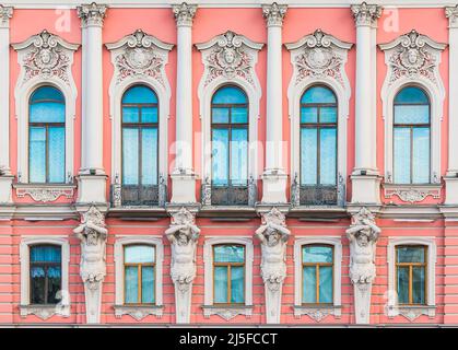 Atlantes und viele Fenster in einer Reihe auf der Fassade des städtischen historischen Wohnhauses Vorderansicht, Sankt Petersburg, Russland Stockfoto