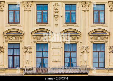 Balkon und mehrere Fenster in einer Reihe auf der Fassade des städtischen historischen Wohnhauses Vorderansicht, Sankt Petersburg, Russland Stockfoto