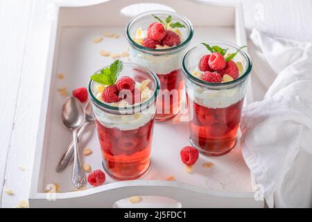 Cremige rote Gelee als Fruchtdessert mit Creme. Gelee mit Schlagsahne und Früchten. Stockfoto