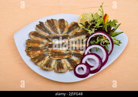 Köstlich und schön gebratener Hamsi-Fisch und Salate, auf einem weißen Essteller Stockfoto