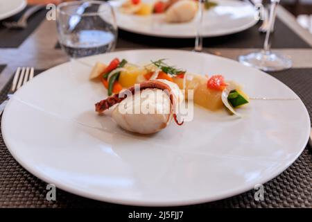 Gegrillter Kabeljau-Fisch und Kraken-Tentakeln mit einer Garnierung aus eingelegtem Gemüse (selektiver Fokus) Stockfoto