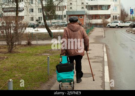 Rentner in Russland. Eine ältere Frau geht die Straße entlang und lehnt sich an einen Stock, um das Gehen zu erleichtern. Ein alter Mann in Moskau. Stockfoto