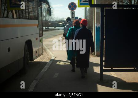 Passagiere an der Bushaltestelle. Die Menschen kommen in den Verkehr. Menschen in Russland nähern sich dem Bus auf der Straße. Stockfoto