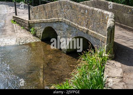 Eine aus Stein gebaute Bogenbrücke über den Wasserbach in Lacock Wiltshire Stockfoto