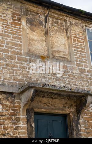 Gebäude aus dem 18.. Jahrhundert mit steinernen Fenstern über der Eingangstür im typisch englischen Dorf Lacock Wiltshire Stockfoto