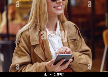 Nahaufnahme einer Frau im Ledermantel mit Smartphone Stockfoto