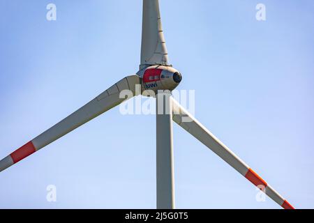 Eine Nahaufnahme einer Windenergieanlage mit drei riesigen Rotorblättern, die gegen einen blauen Himmel isoliert sind Stockfoto