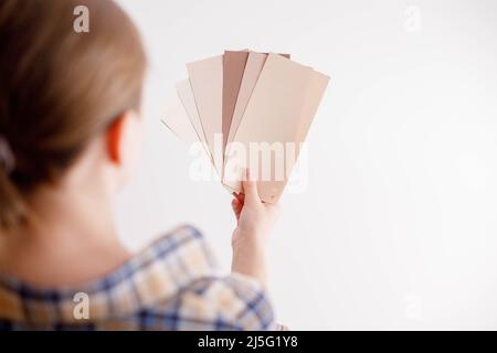 Die junge Frau hält Farbproben für die Wand in der Hand Stockfoto
