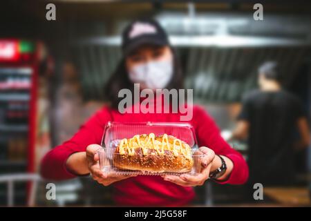 Ein Café-Mitarbeiter gibt eine Bestellung von Fast Food in einer Schachtel. Stockfoto