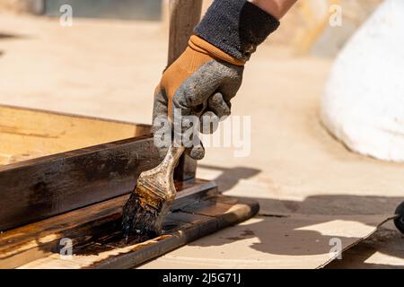 Mann, der an der Restaurierung alter Möbel mit Bitumen judaicum arbeitet. Konzept für Holzpflege und Abdichtung Stockfoto