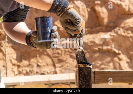 Mann, der an der Restaurierung alter Möbel mit Bitumen judaicum arbeitet. Konzept für Holzpflege und Abdichtung Stockfoto