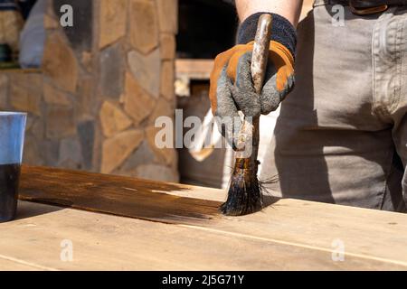 Mann, der an der Restaurierung alter Möbel mit Bitumen judaicum arbeitet. Konzept für Holzpflege und Abdichtung Stockfoto