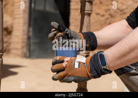 Mann, der an der Restaurierung alter Möbel mit Bitumen judaicum arbeitet. Konzept für Holzpflege und Abdichtung Stockfoto