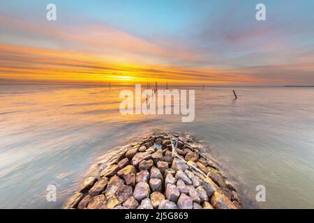 Typischer Bau von Basalt-Wellenbrechern am IJsselmeer in der Nähe der Stadt Hindeloopen in der Provinz Friesland bei Sonnenuntergang, Niederlande. Stockfoto