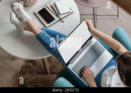 Junge Frau mit Laptop-Bildschirm mockup zu Hause arbeiten, Telearbeit Stockfoto