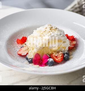 Meringuerolle mit Erdbeeren, Blaubeeren, Himbeeren und Preiselbeeren. Dessert mit frischen Beeren auf dem Tisch dekoriert. Stockfoto