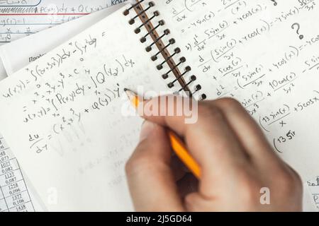 Mathematische Formeln sind in einem Notizbuch mit Mann in Bleistift geschrieben Stockfoto