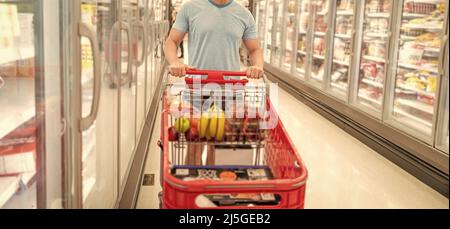 Cropped Mann mit Einkaufswagen kaufen Lebensmittel im Lebensmittelgeschäft, Einkaufen Stockfoto