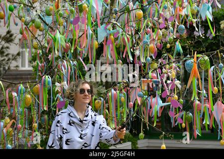 Moskau, Russland. 23. April 2022. Eine Frau macht ein Selfie unter einem mit Ostereiern geschmückten Baum während des traditionellen Osterbasars in Moskau, Russland, am 23. April 2022. Quelle: Alexander Zemlianichenko Jr/Xinhua/Alamy Live News Stockfoto