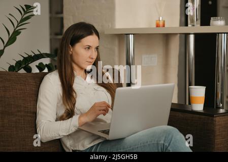 Eine Geschäftsfrau, die von zu Hause aus auf dem Sofa an ihrem Laptop arbeitet. Stockfoto