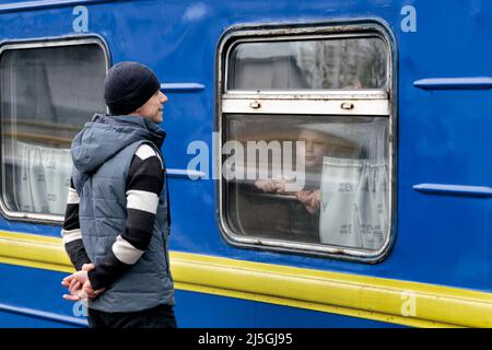 Ein Mann steht auf dem Bahnsteig, als er sich von seiner Familie und seinen Freunden verabschiedet, die er in einem Zug gesehen hat, der vom Bahnhof Odessa-Holovna nach Uschhorod in der Westukraine an der slowakischen Grenze abfährt. Stockfoto