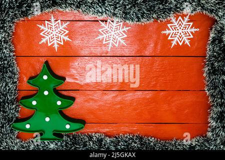 Weihnachten Zusammensetzung auf rote Holzbrett mit Christmas Garland und Dekorationen. Kreative Zusammensetzung mit Rand kopieren und Raum, Ansicht von oben, flach. Stockfoto