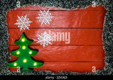 Weihnachten Zusammensetzung auf rote Holzbrett mit Christmas Garland und Dekorationen. Kreative Zusammensetzung mit Rand kopieren und Raum, Ansicht von oben, flach. Stockfoto