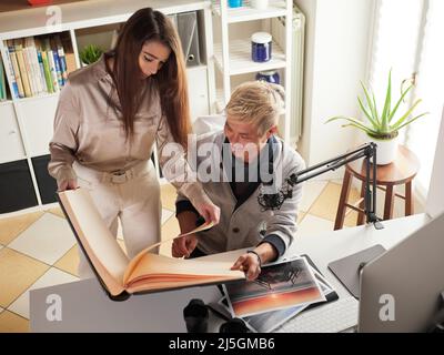 Fotografen, die am Arbeitsplatz mit zwei Computern im Studio mit einem Laptop arbeiten Stockfoto